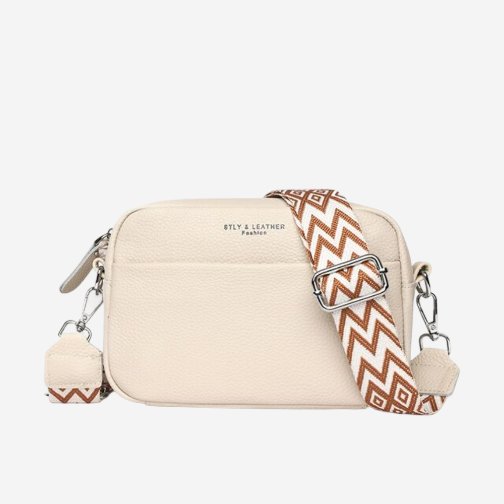 A beige crossbody bag with a zigzag patterned strap.