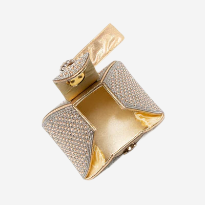 A gold-colored, diamond-encrusted clutch purse with a gold clasp and a gold-colored, diamond-encrusted ring attached to it.