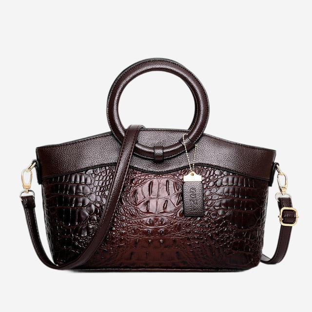 A brown leather handbag with a crocodile skin texture, featuring a round handle and a gold-colored metal clasp.