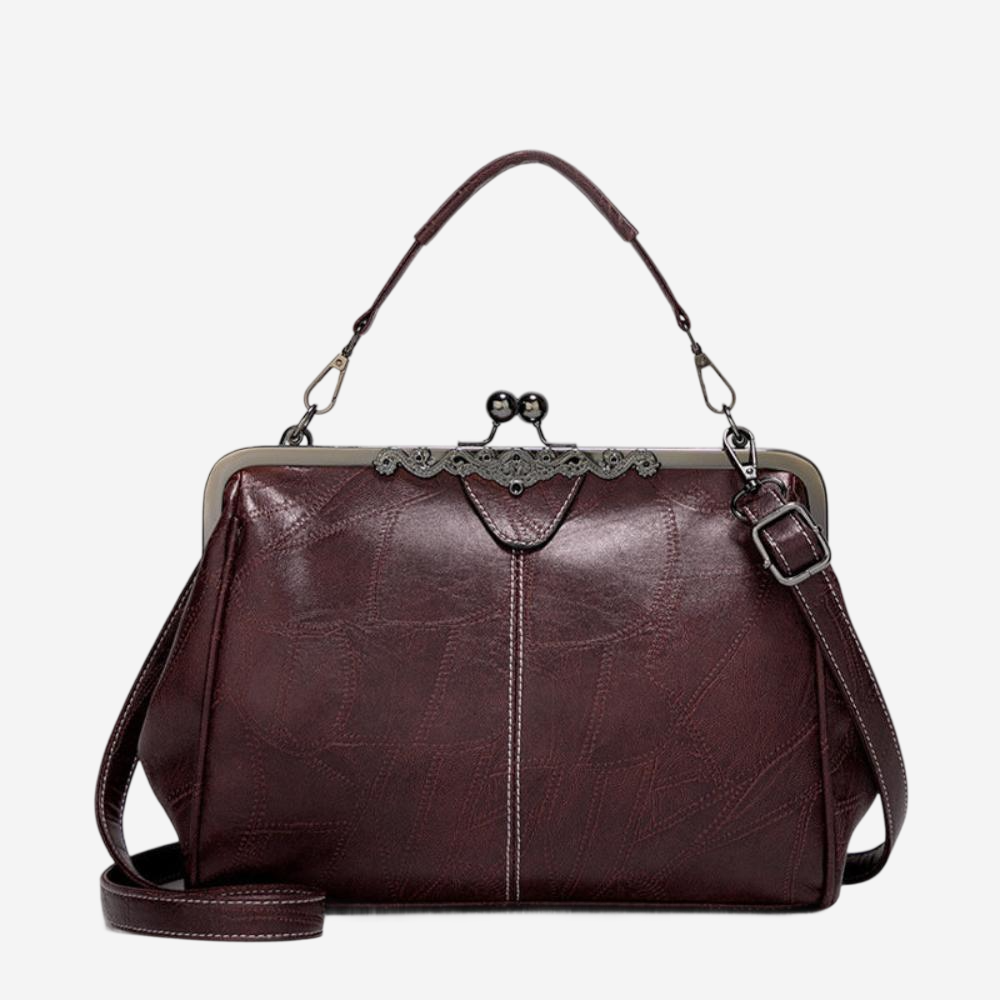 A burgundy leather handbag with a metal clasp and handle, featuring a lace-like design on the front.