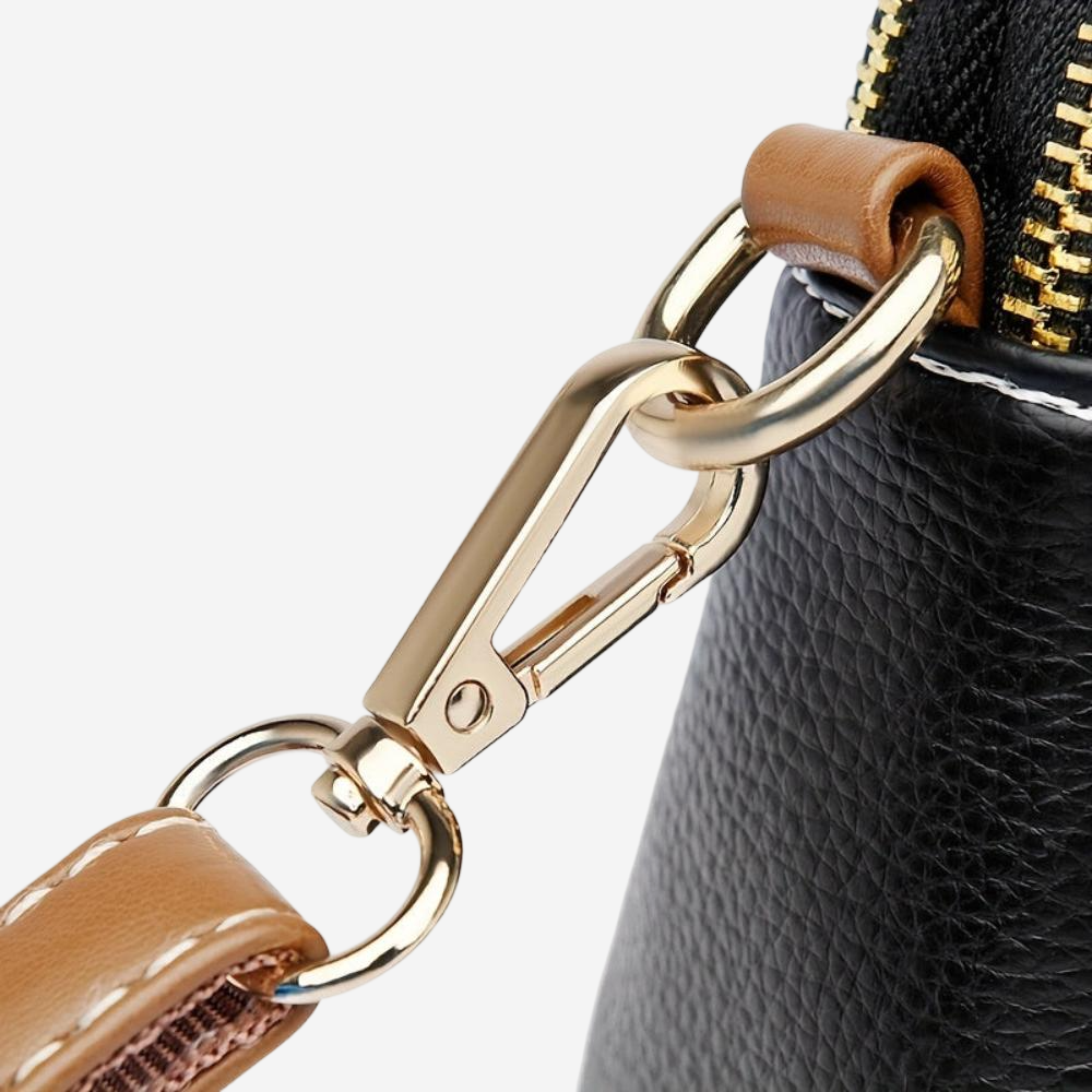 A close-up view of a black leather handbag with a gold metal clasp and zipper.