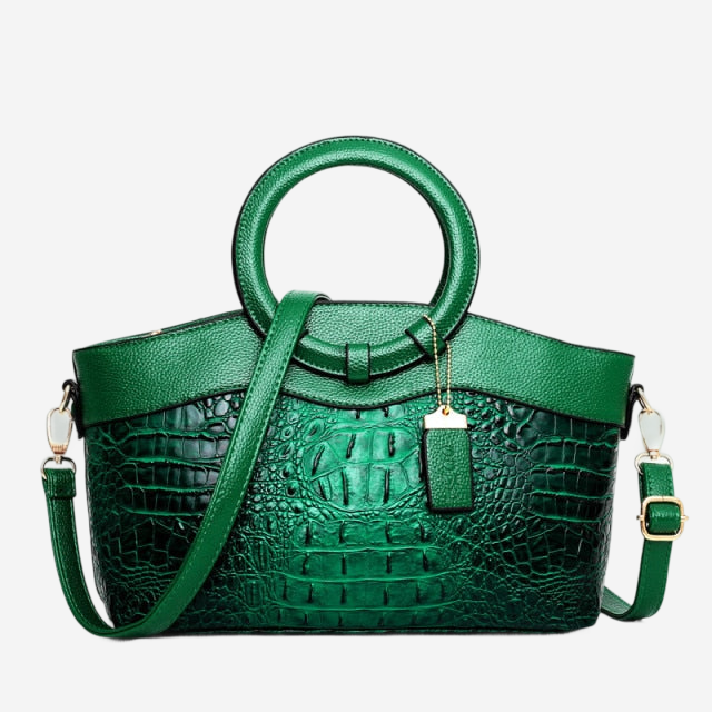 A green handbag with a crocodile skin texture and a round handle.