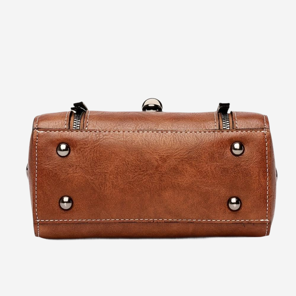 A brown leather handbag with metal hardware and zippers.