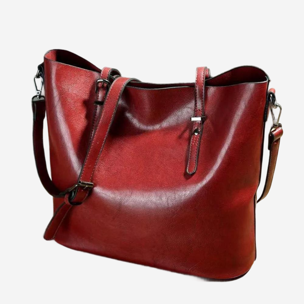 A red leather tote bag with a shoulder strap and a front zipper closure.