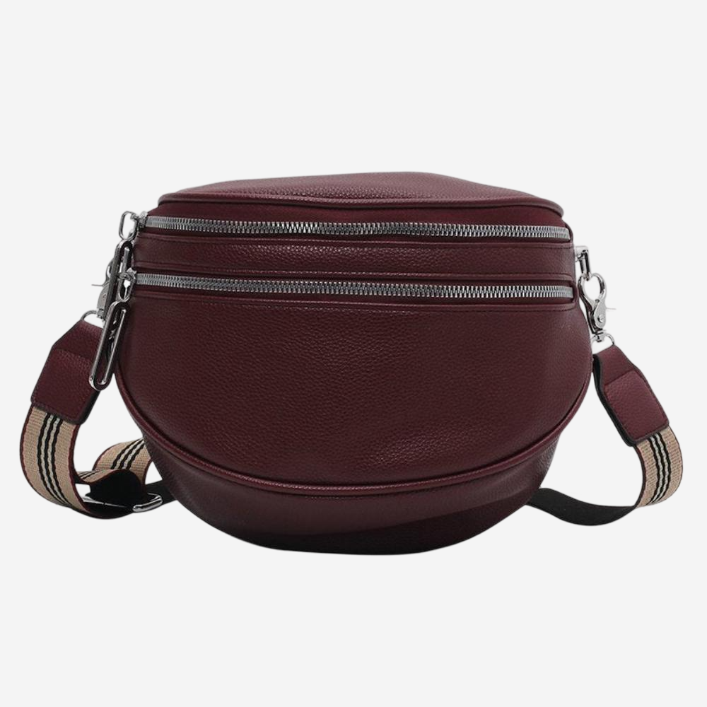 A burgundy leather crossbody bag with multiple zippers and a striped strap.