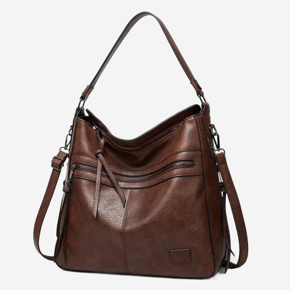 A brown leather handbag with multiple zippers and a curved shoulder strap.