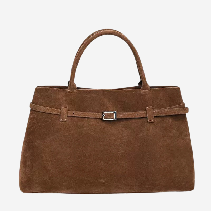 A brown suede handbag with a metal buckle detail and a curved handle.