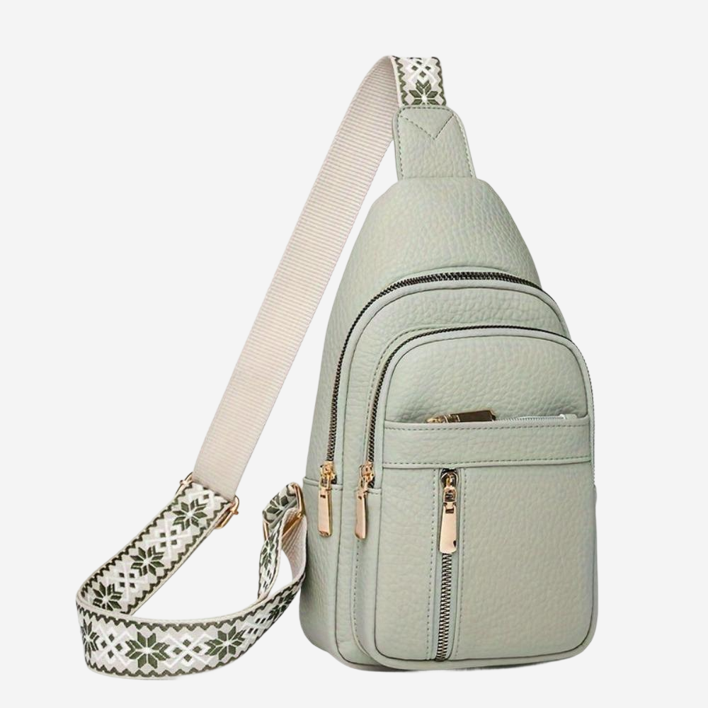 A light green crossbody bag with a white strap and zipper closure.