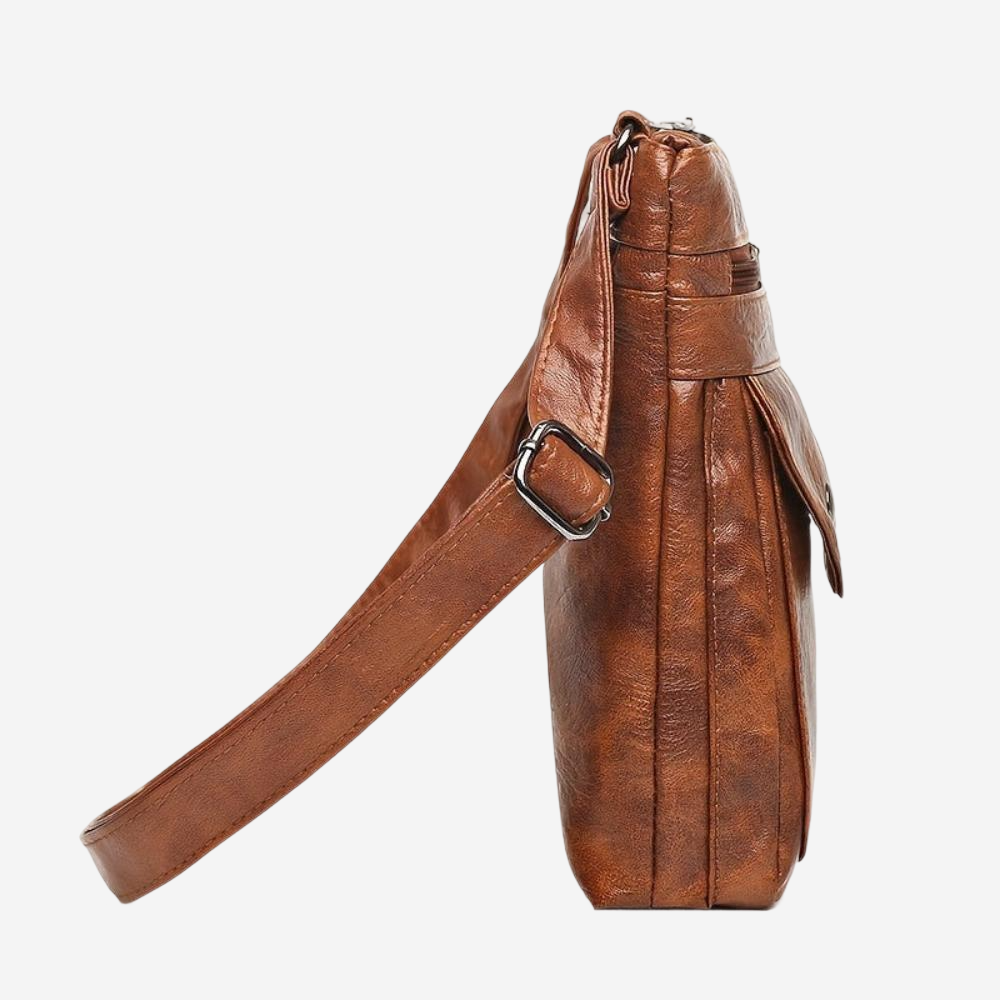 A brown leather crossbody bag with a metal zipper closure and a long strap.