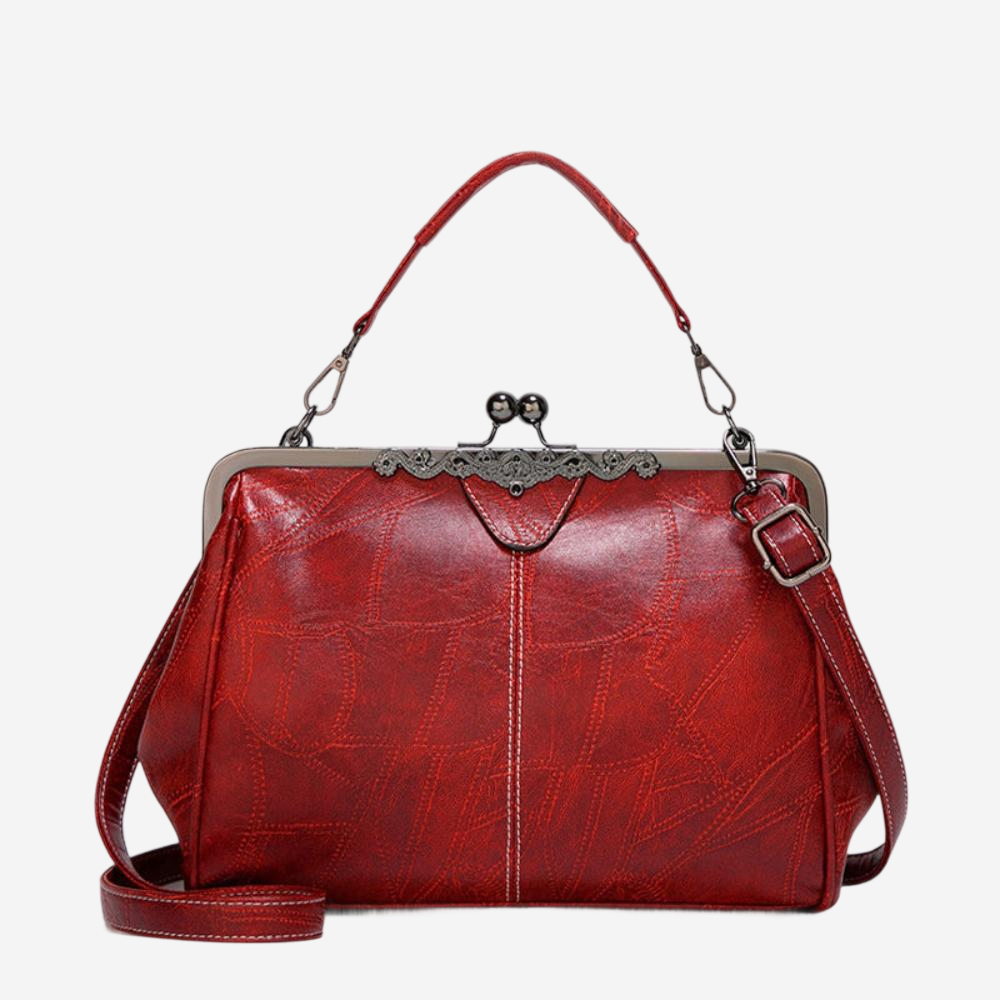 A red leather handbag with a metal clasp and handle, featuring a distinctive design and a clasp closure.