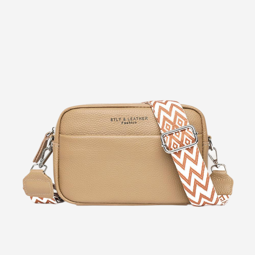 A tan leather crossbody bag with a patterned strap and the text "STLY & LEATHER Fashion" printed on it.