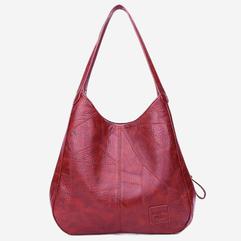 A red leather handbag with a curved handle and a small tag on the front.