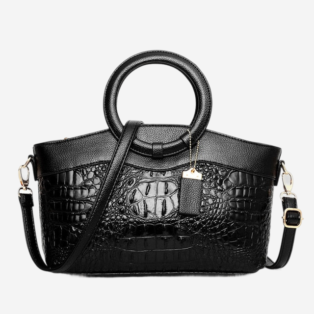 A black leather handbag with a crocodile skin texture, featuring a round handle and a gold-colored tag.