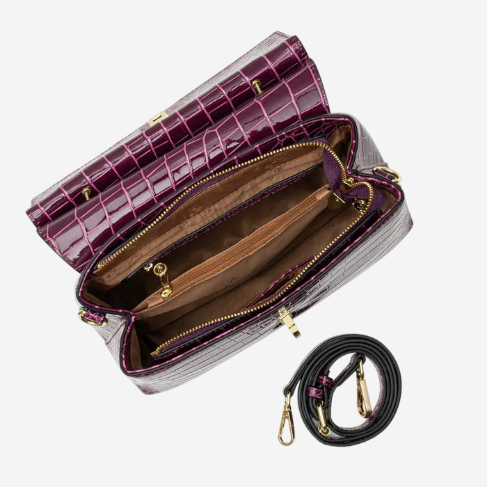 an open purple handbag with a black strap and gold hardware, including a zipper and clasp.