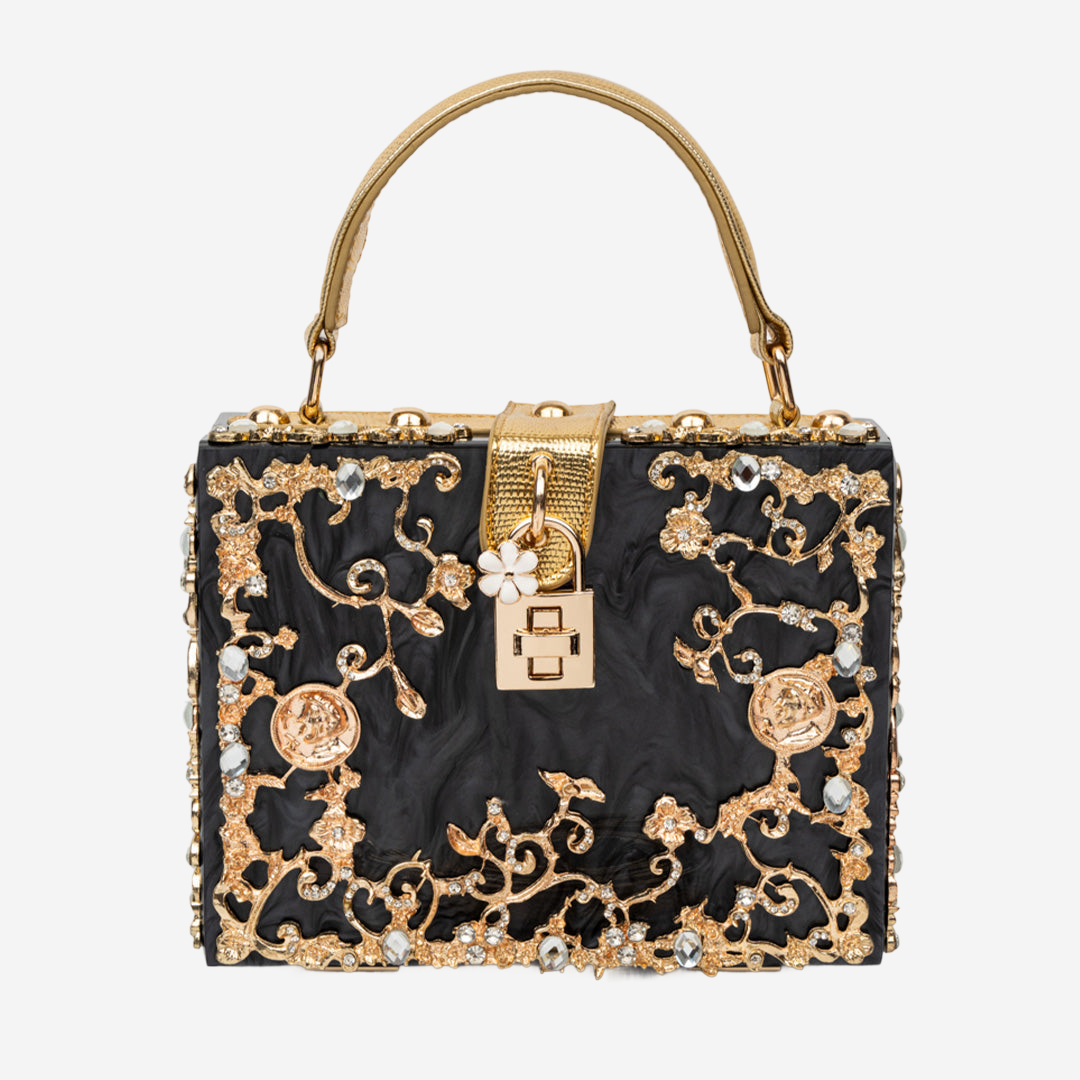 A black handbag with gold floral and crystal embellishments, including a lock-shaped clasp and a handle.