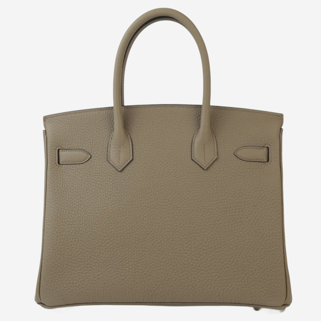 A tan leather handbag with a curved handle and two small pockets on the front.