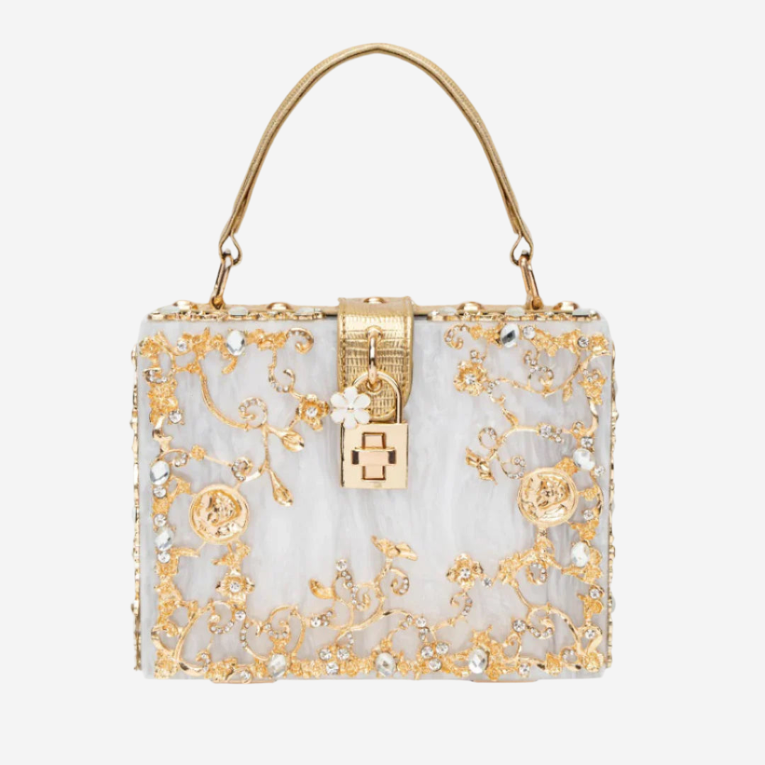 A white and gold handbag with intricate floral designs and a gold lock.