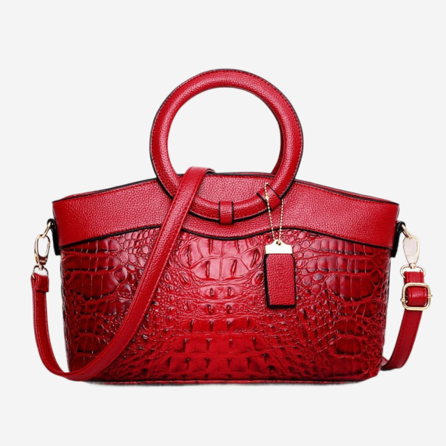 A red handbag with a crocodile skin texture and a round handle.