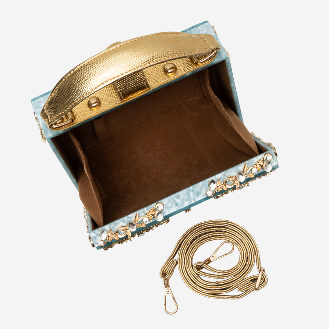 A small, ornate handbag with a gold handle and a gold chain strap is shown in the image.