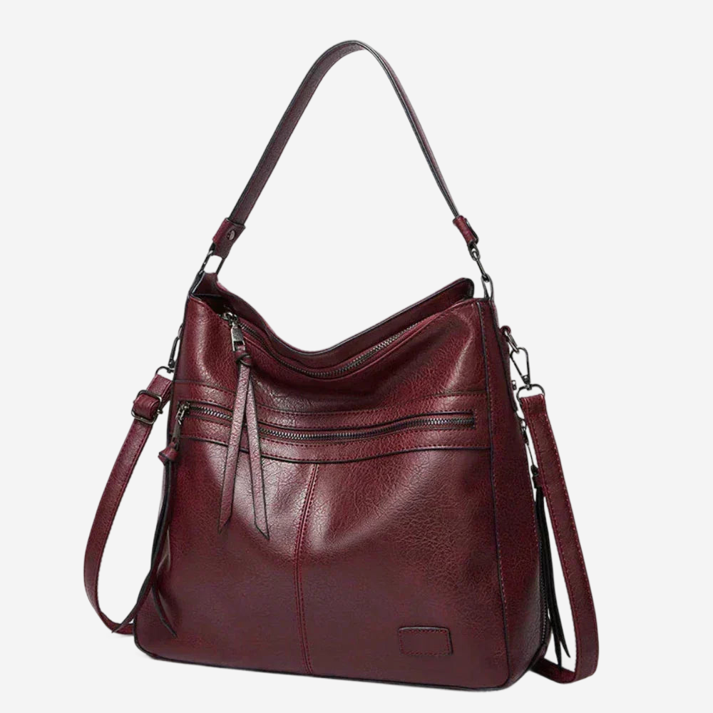 A burgundy leather handbag with multiple zippers and a curved shoulder strap.
