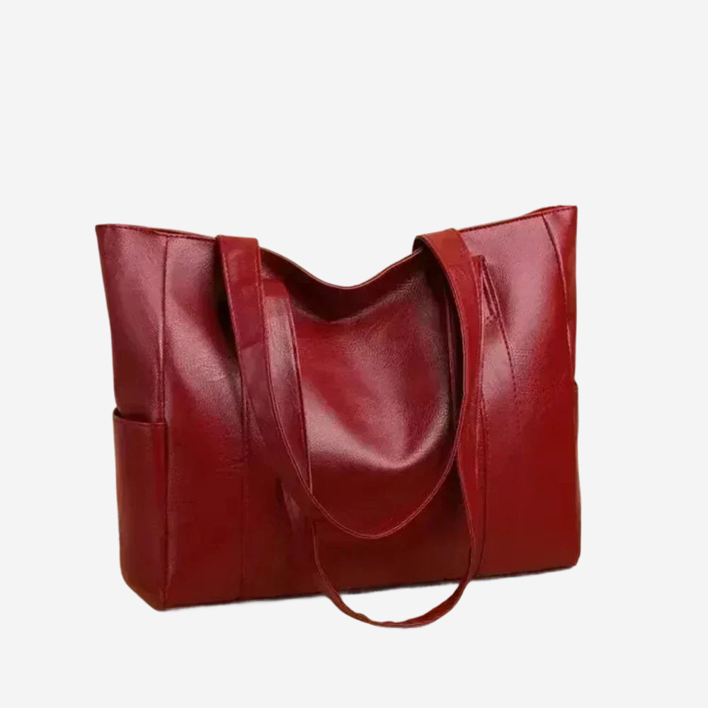 A red leather tote bag with a curved handle and two pockets.