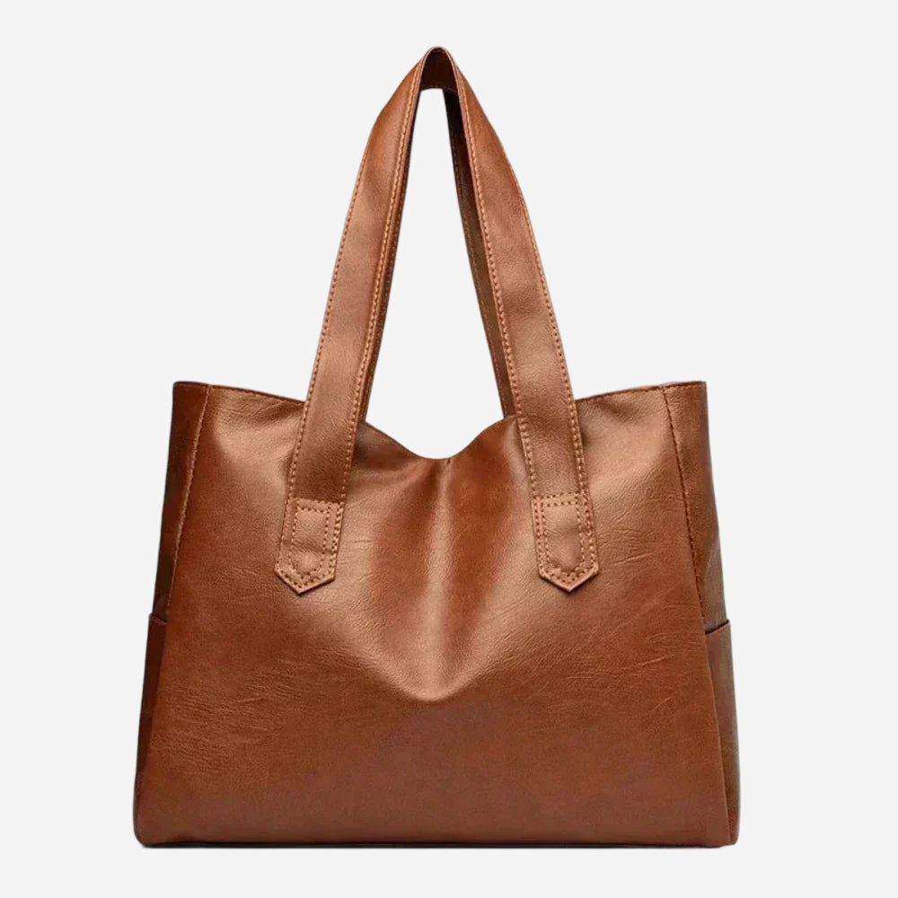 A brown leather tote bag with a curved handle and two shoulder straps.