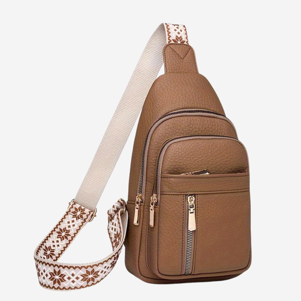 A brown leather crossbody bag with multiple pockets and zippers, featuring a white strap with a floral pattern.