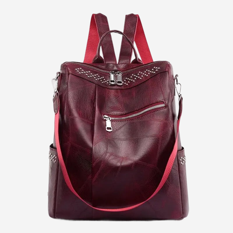 A burgundy leather backpack with a red strap and multiple zippers.