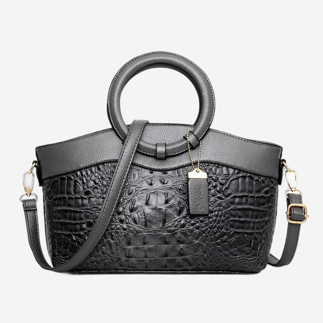 A black leather handbag with a crocodile skin texture, featuring a round handle and a gold-colored metal clasp.