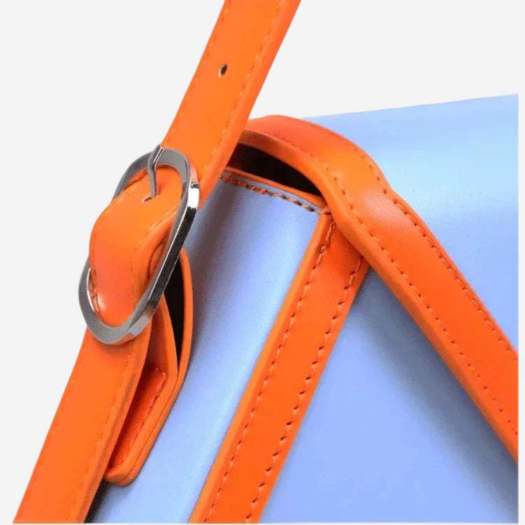 A close-up view of a blue and orange leather strap with a metal buckle, suggesting a stylish accessory.