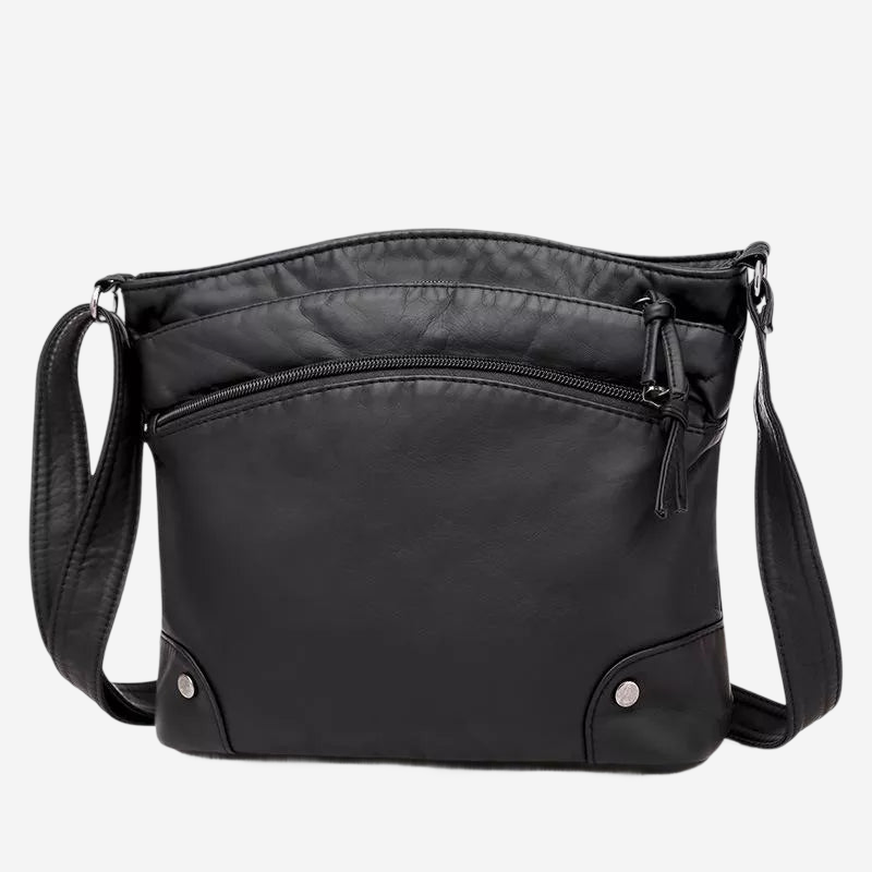A black leather crossbody bag with a zipper closure and two metal buttons on the front.
