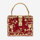 A red handbag with gold floral and crystal embellishments, including a lock-shaped clasp and a gold handle.