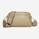 A tan leather crossbody bag with a patterned strap and a zipper closure.