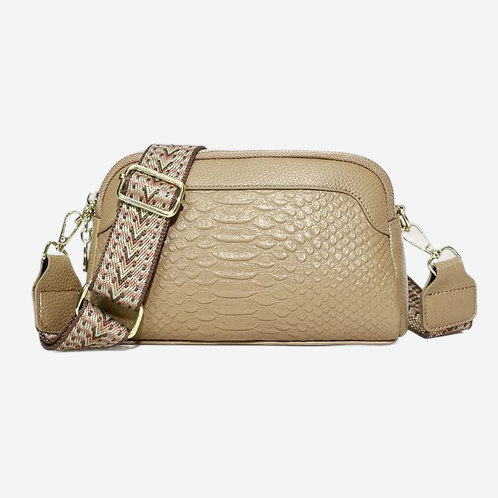 A tan leather crossbody bag with a patterned strap and a zipper closure.