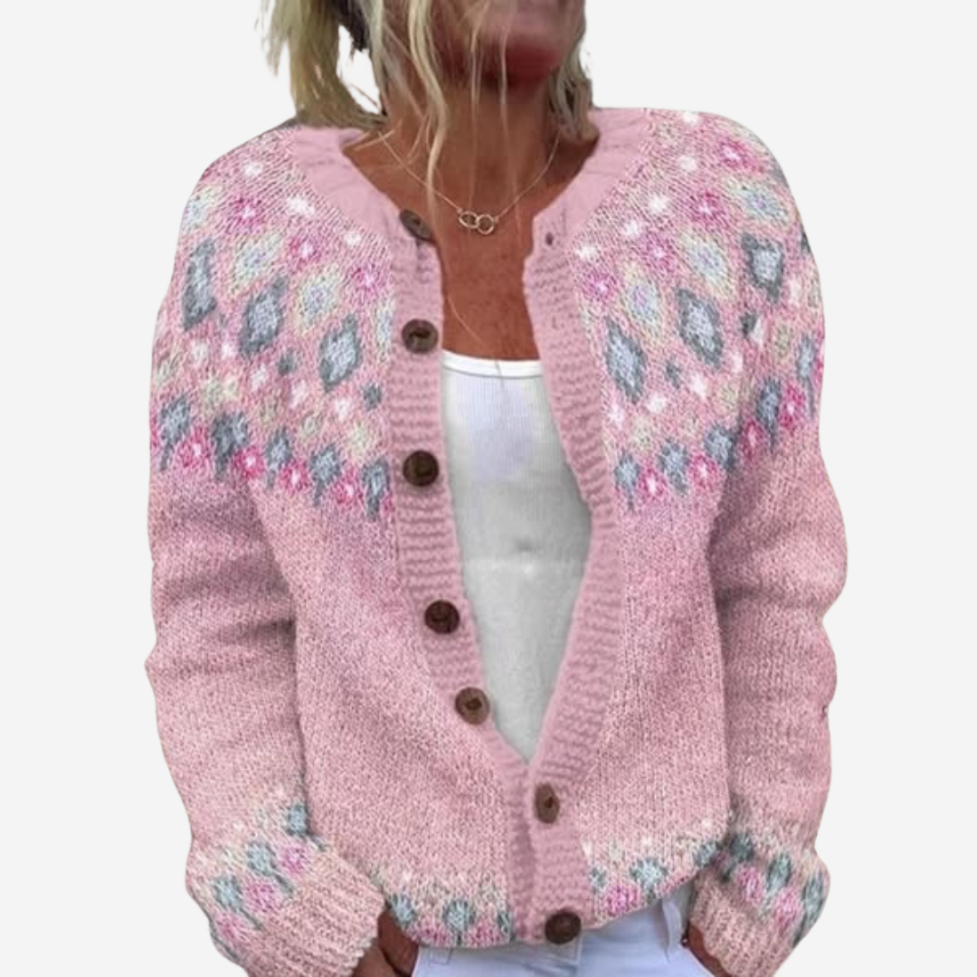A woman wearing a pink knitted cardigan with a floral pattern.
