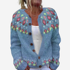 A woman wearing a blue knitted cardigan with colorful floral patterns.