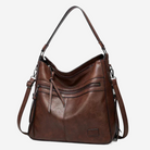 A brown leather handbag with multiple zippers and a curved shoulder strap.