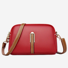 A red crossbody bag with a brown leather strap and a gold-colored metal clasp.