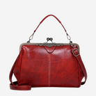A red leather handbag with a metal clasp and handle, featuring a distinctive design and a clasp closure.
