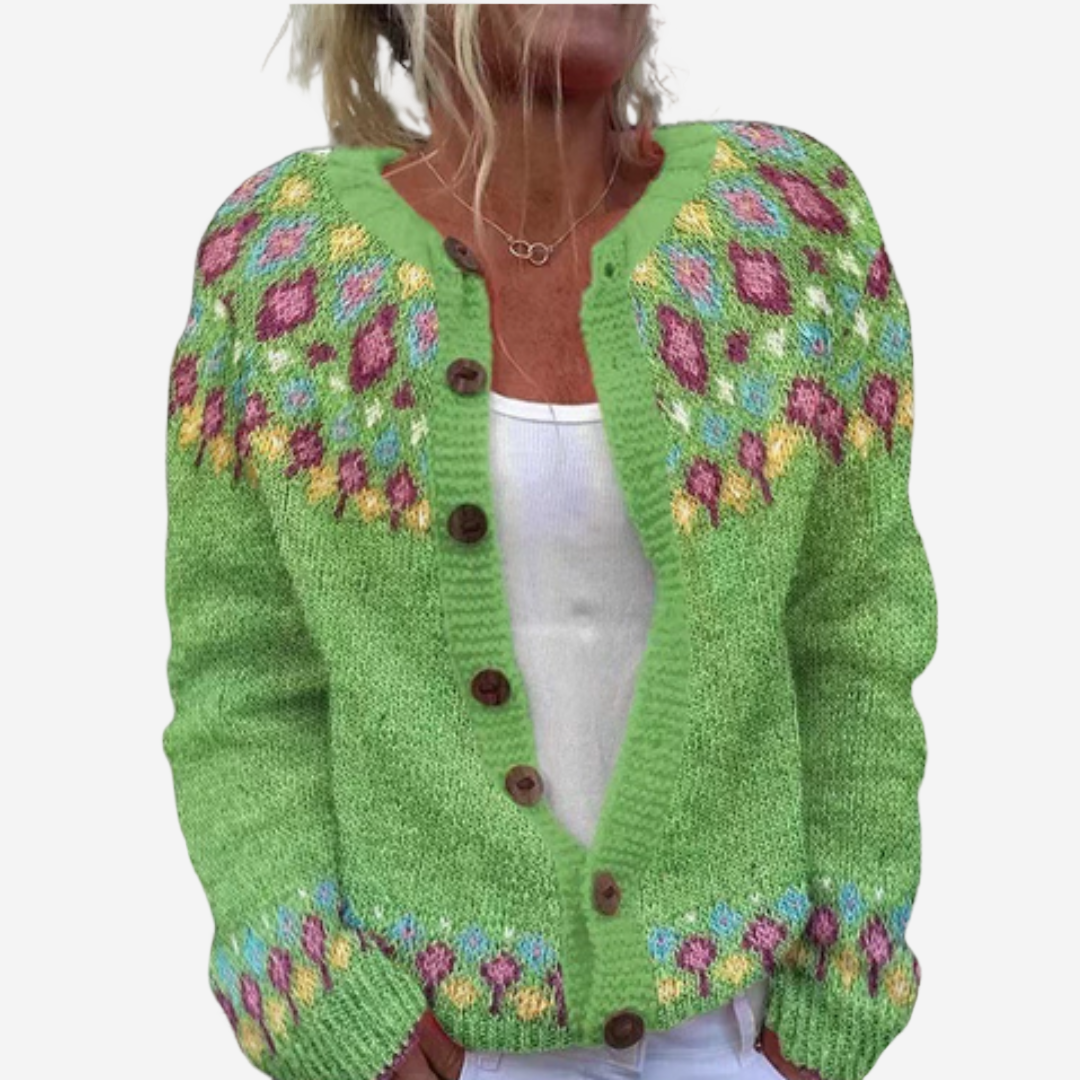 A woman wearing a green knitted cardigan with colorful floral patterns on the front.
