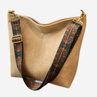 A tan leather handbag with a patterned strap and a gold metal clasp.