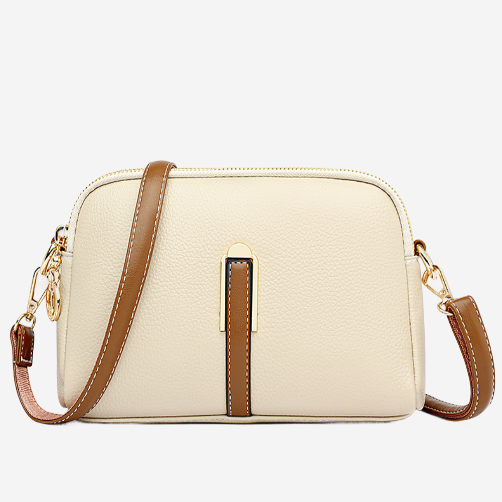 A beige leather crossbody bag with a brown leather strap and a gold-colored metal clasp.