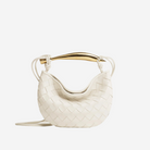 A white woven handbag with a gold handle and strap.