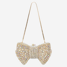 A handbag with a gold chain strap and a large, intricately designed bow made of sparkling rhinestones.