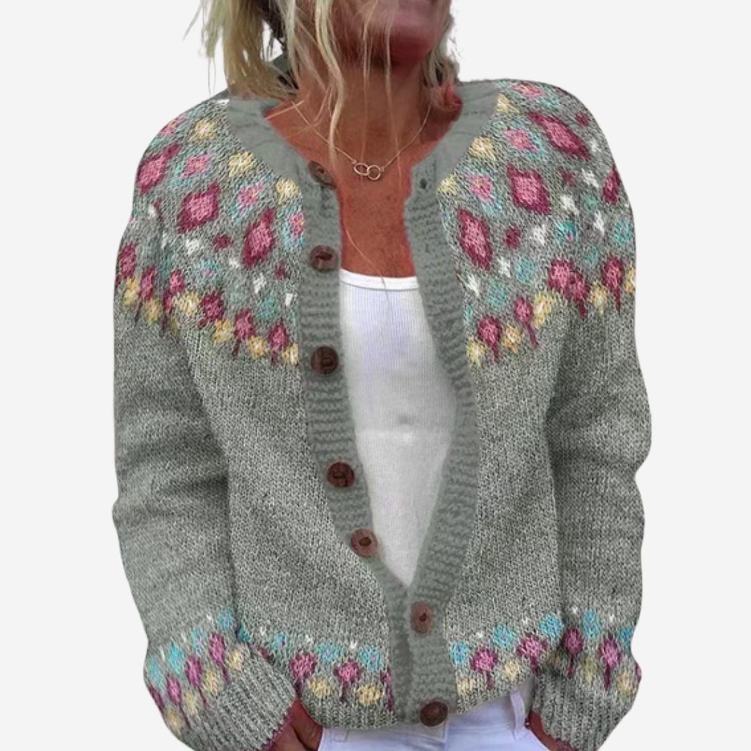 A woman wearing a gray knitted cardigan with colorful floral patterns on the front.