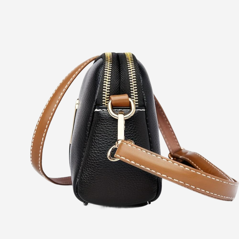A black crossbody bag with a brown leather strap and zipper closure.