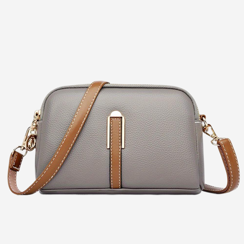 A gray leather crossbody bag with a brown leather strap and a gold-colored metal clasp.