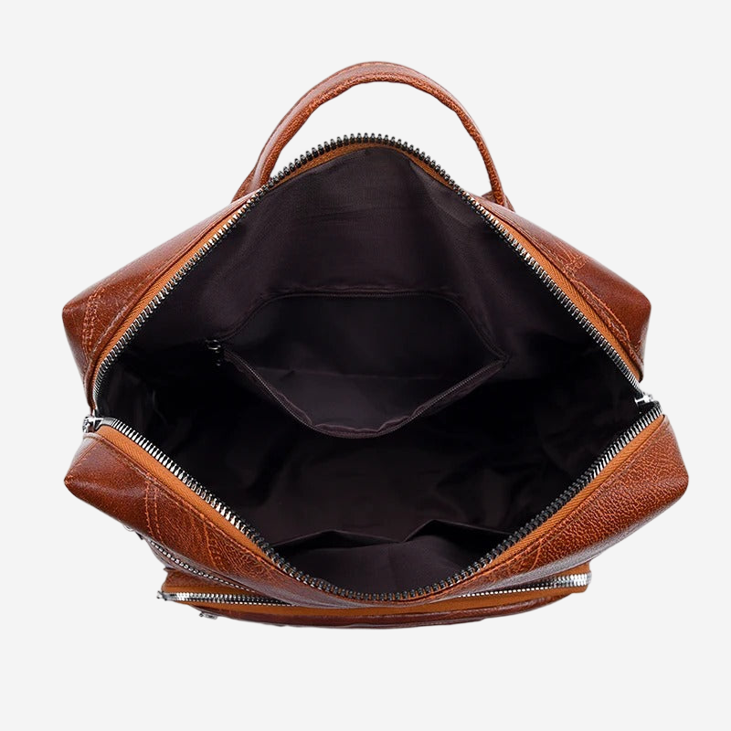 the interior of a brown leather backpack with a zipper closure and two zippered pockets.
